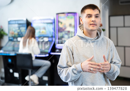 Young man in hall with slot machines Young man in hall with slot machines 139477828