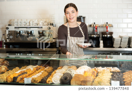 Bakery saleswoman offers to buy delicious pastry 139477848