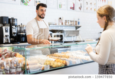 man coffee shop worker offers fresh pastries to customers man coffee shop worker offers fresh pastries to customers 139477850