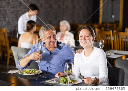 Elderly man resting in restaurant with young female companion 139477865
