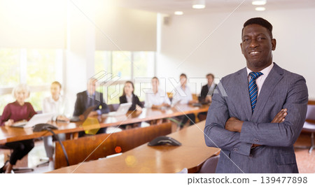 Portrait of successful african american businessman in front of team of businessmen in meeting room 139477898