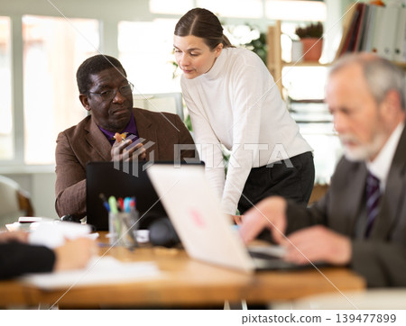 Management meeting in company office. Secretary distributes folders with documents 139477899