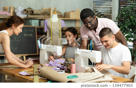 Experienced sewing instructor overseeing students in fashion course Experienced sewing instructor overseeing students in fashion course 139477903