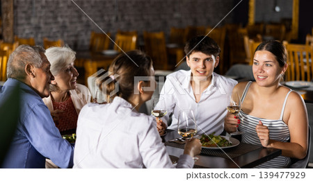 Young couple enjoying dinner with senior parents in restaurant Young couple enjoying dinner with senior parents in restaurant 139477929