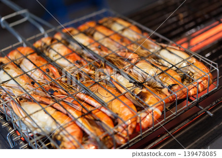 Fresh grilled river prawns cooking on metal barbecue rack with glowing heat seafood street food dinner closeup with smoky atmosphere and appetizing texture 139478085