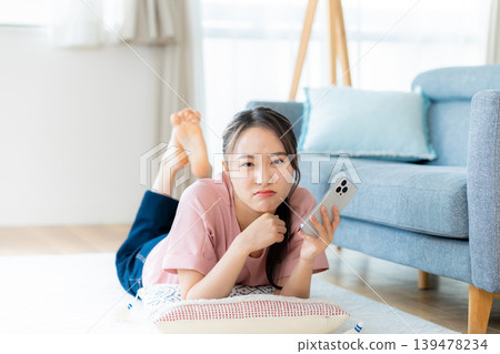 在房間裡操作智慧型手機的年輕女子 在房間裡操作智慧型手機的年輕女子 139478234