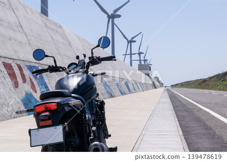 A road lined with windmills along the coast and motorcycles A road lined with windmills along the coast and motorcycles 139478619