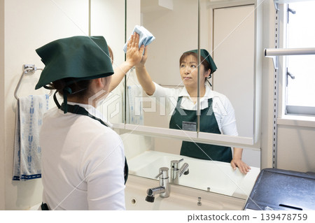 一位清潔阿姨正在擦拭浴室鏡子。 一位清潔阿姨正在擦拭浴室鏡子。 139478759