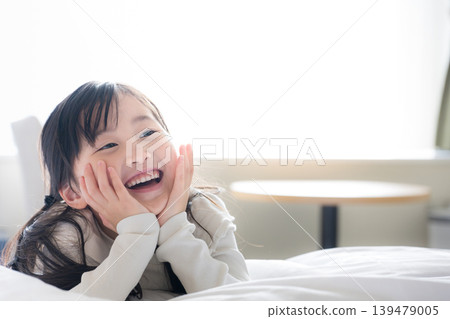 一張特寫照片，展現了孩子純真的快樂：一個女孩臉上帶著笑容，手托著下巴，興奮地享受著快樂時光。 139479005