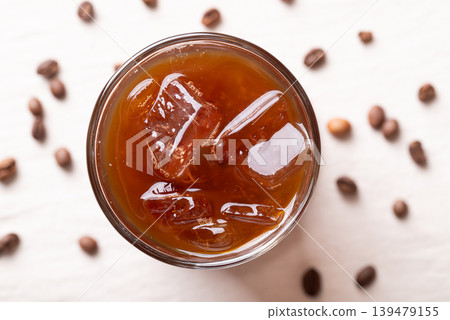 Iced americano coffee in a glass with roasted coffee beans on white fabric Iced americano coffee in a glass with roasted coffee beans on white fabric 139479155