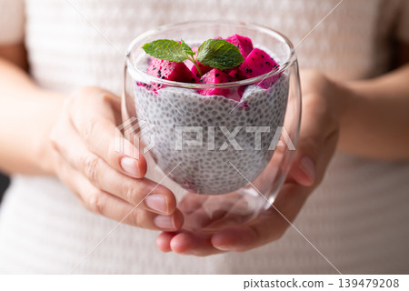 Chia pudding topped with fresh dragon fruit in a glass holding by woman hand, Healthy eating 139479208