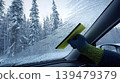 Hand scraping frost from car windshield on winter morning 139479379