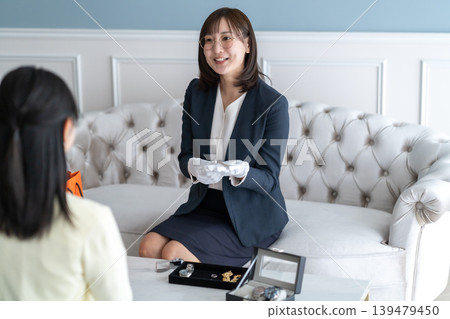 Title candidate: A female appraiser who smiles and politely explains the results of the watch appraisal. 139479450