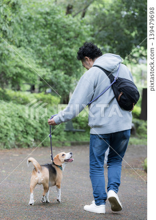 A man who owns a beagle, a smiling portrait of him walking his dog, a lifestyle of living with animals, images of training and discipline. A man who owns a beagle, a smiling portrait of him walking his dog, a lifestyle of living with animals, images of training and discipline. 139479698