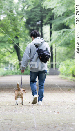 一位擁有比格犬的男士，一張他牽著狗散步的微笑照片，一種與動物共同生活的生活方式，訓練和紀律的畫面。 139479701