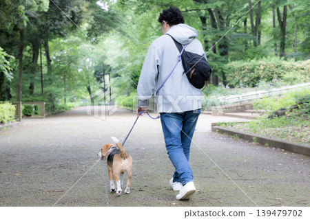 一位擁有比格犬的男士，一張他牽著狗散步的微笑照片，一種與動物共同生活的生活方式，訓練和紀律的畫面。 139479702