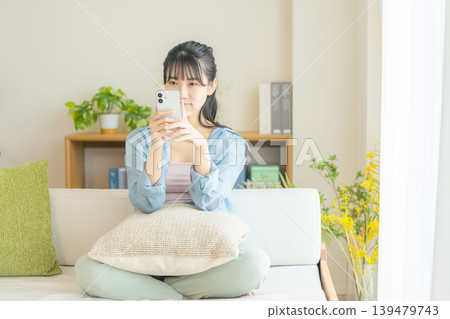 年輕女子在客廳看智慧型手機 139479743