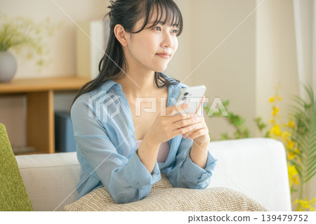 年輕女子在客廳看智慧型手機 139479752