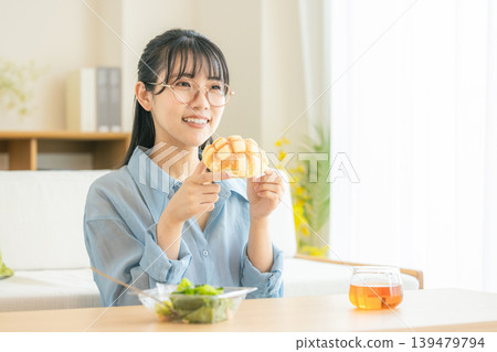 A young woman eating melon bread 139479794