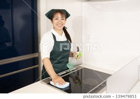 一名從事家事清潔工作的女子正在擦拭電磁爐。 一名從事家事清潔工作的女子正在擦拭電磁爐。 139479851