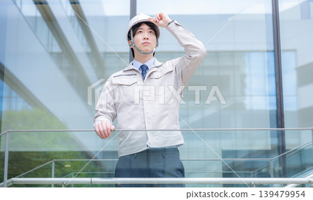 一位年輕男子的肖像,他戴著安全帽,仰望著未來和希望,就像一位建築經理,背景是一棟建築物。 一位年輕男子的肖像,他戴著安全帽,仰望著未來和希望,就像一位建築經理,背景是一棟建築物。 139479954