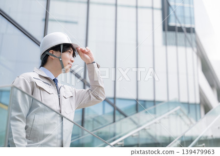 Portraits of young men, such as construction managers, wearing helmets and looking up at the future and hope against a backdrop of buildings; profiles of young men. Portraits of young men, such as construction managers, wearing helmets and looking up at the future and hope against a backdrop of buildings; profiles of young men. 139479963