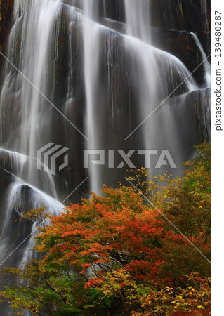 Autumn leaves shining against the blue sky at the waterfall Autumn leaves shining against the blue sky at the waterfall 139480287