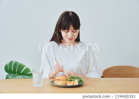 一位年輕女子一邊吃早餐一邊微笑 139480391