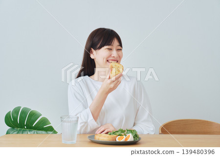 微笑的年輕女子正在享用早餐 139480396