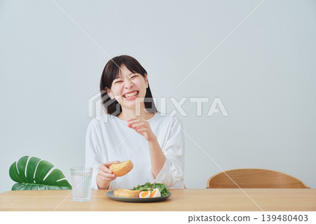 Smiling young woman enjoying breakfast 139480403