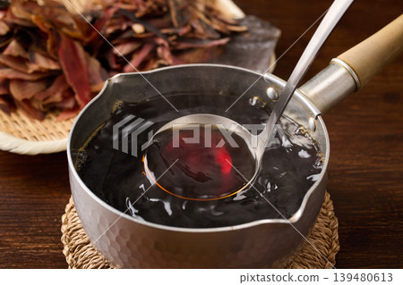 Scoop the soba dipping sauce with a ladle. 139480613