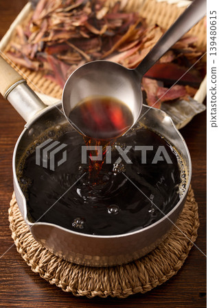 Scoop the soba dipping sauce with a ladle. 139480615