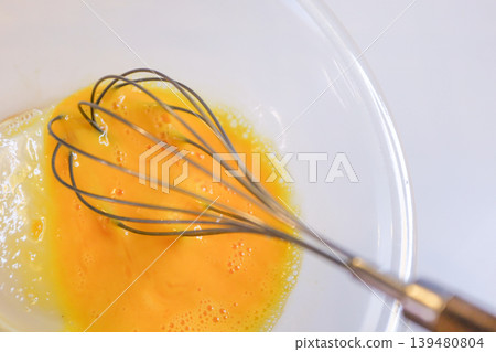 Mix the egg yolks with a whisk - preparation for making cream puffs. Mix the egg yolks with a whisk - preparation for making cream puffs. 139480804