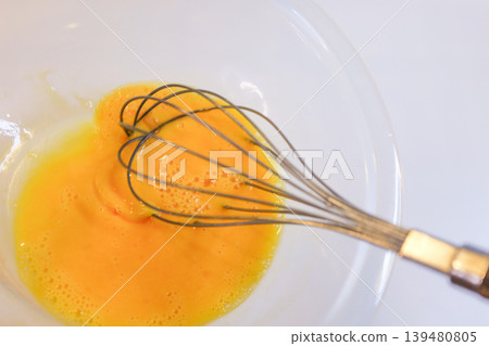 Mix the egg yolks with a whisk - preparation for making cream puffs. Mix the egg yolks with a whisk - preparation for making cream puffs. 139480805