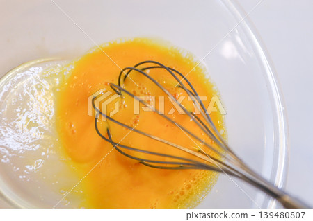 Mix the egg yolks with a whisk - preparation for making cream puffs. Mix the egg yolks with a whisk - preparation for making cream puffs. 139480807
