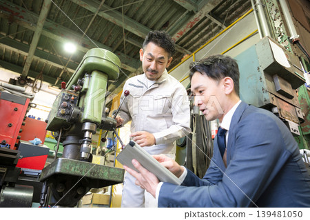 一名工人和一名銷售人員正在講解生產機械的維護、新機械的購買（資本投資）和融資。 139481050