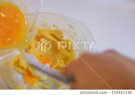 Making choux pastry by mixing in egg yolks. Making choux pastry by mixing in egg yolks. 139481146