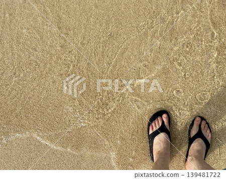 沖繩海灘的海岸線和穿著涼鞋的雙腳 沖繩海灘的海岸線和穿著涼鞋的雙腳 139481722