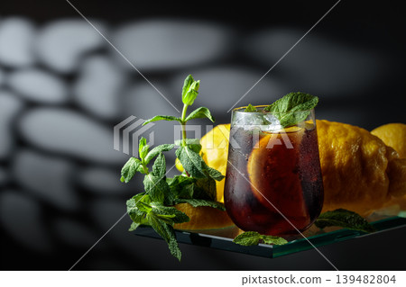 Cocktail with lemon wedges, ice and mint in misted glass. Cocktail with lemon wedges, ice and mint in misted glass. 139482804