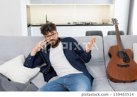 Man playing acoustic guitar showing okay sign relaxing indoors Man playing acoustic guitar showing okay sign relaxing indoors 139483514