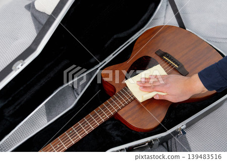 Hand cleaning acoustic guitar body with microfiber cloth Hand cleaning acoustic guitar body with microfiber cloth 139483516