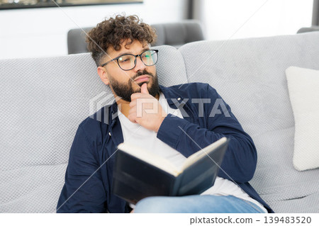 Man reading book and deeply thinking on sofa 139483520