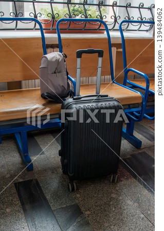 Black suitcase on wheels at railway station waiting area Black suitcase on wheels at railway station waiting area 139484062