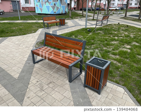 Modern wooden park bench with trash bin in residential courtyard Modern wooden park bench with trash bin in residential courtyard 139484068
