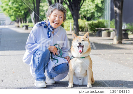 一位老婦人正牽著她的寵物柴犬散步。 139484315