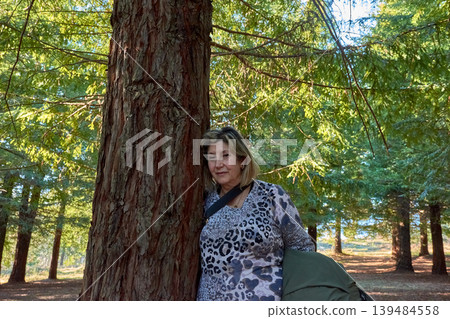 Woman connecting with nature while touching a redwood tree in the forest Woman connecting with nature while touching a redwood tree in the forest 139484558