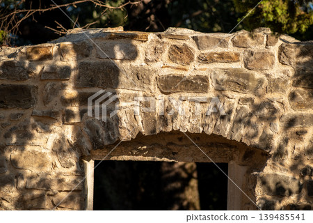 Sunlit rustic stone archway with tree shadows Sunlit rustic stone archway with tree shadows 139485541
