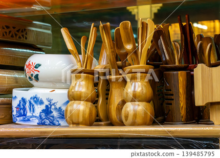 Wooden kitchen utensils display on shop shelf with ceramic bowls 139485795