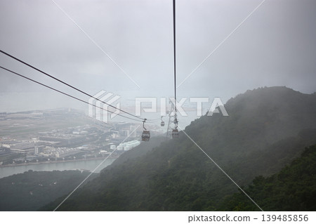 Cable car gondolas of Ngong Ping 360, suspended on a ropeway in dense fog, on Lantau Island in SAR Hong Kong, China Cable car gondolas of Ngong Ping 360, suspended on a ropeway in dense fog, on Lantau Island in SAR Hong Kong, China 139485856