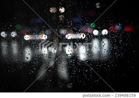 Rain on Window at Night with Blurred City Lights. Moody Urban Background. Raindrops Rain on Window at Night with Blurred City Lights. Moody Urban Background. Raindrops 139486159